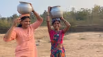 Two women balance large pots on their heads